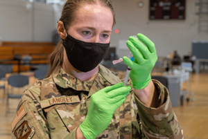 U.S. Air Force Maj. Rachel Langley, 310th Space Wing flight surgeon, fills a syringe with Moderna COVID-19 vaccine at the base gym