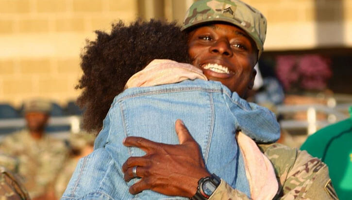 Military personnel hugs family member