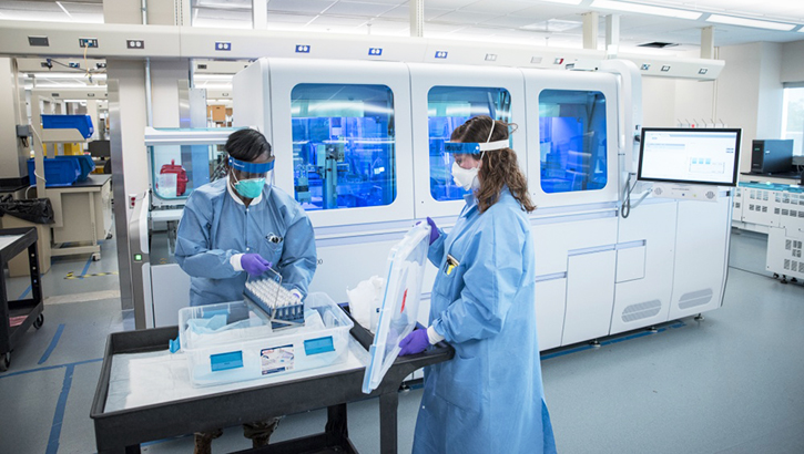Image of Two technicians in full PPE in a lab.