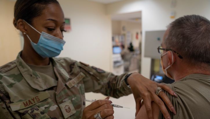 Image of Military health personnel wearing a face mask administering the COVID-19 vaccine.