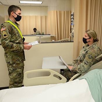 Military health personnel wearing face mask speaking to each other