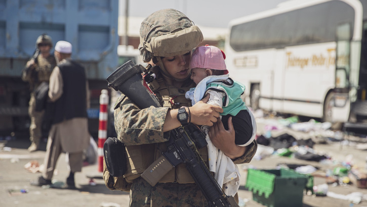 A U.S. Marine carries a baby as the family processes through the Evacuation Control Center during an evacuation at Hamid Karzai International Airport, Kabul, Afghanistan, Aug. 28. (U.S. Marine Corps photo by Staff Sgt. Victor Mancilla)