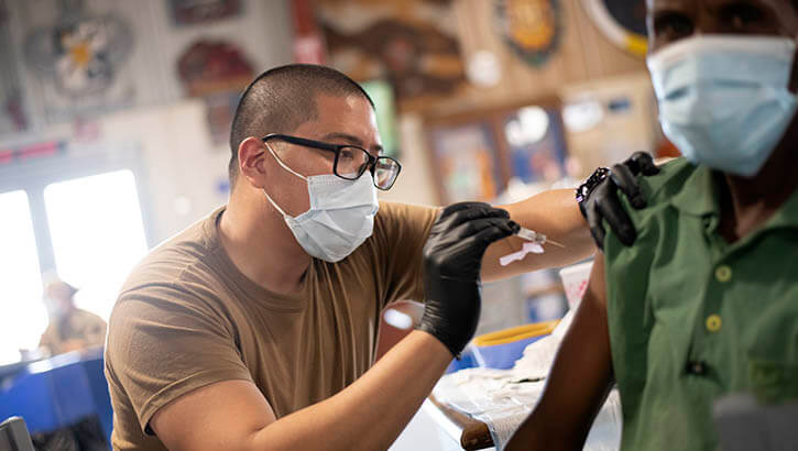 Image of Navy Petty Officer 3rd Class Jemuel Macabali, from San Diego, Calif., gives the COVID-19 vaccine to staff at Camp Lemonnier, in Djibouti, Aug. 13, 2021. .