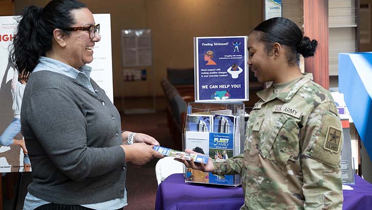 Dr. Diaz discusses the importance of mental fitness with U.S. Army Pvt. 2 Kaliyah Rowan at the Mental Fitness Information table during Staff Resiliency Week at Walter Reed. Diaz says prioritizing mental health is key to building resilience, and shared five ways staff members can do just that in honor of Mental Health Awareness Month. (Photo by U.S. Navy Petty Officer 1st Class Jesse Sharpe, Walter Reed National Military Medical Center)
