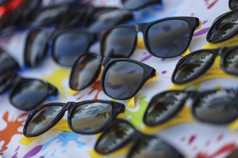Group of sunglasses displayed face up, laying on a tarp.